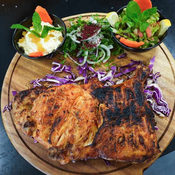 Grilled chicken with two side salads, one with mint and lemon, the other with carrots and raisins.